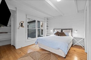 Ein Schlafzimmer mit einem Bett, Nachttischen, einem Fenster und einem Deckenventilator.