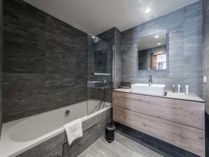 A modern bathroom with a bathtub, a glass-enclosed shower, a vanity with a mirror, and a trash bin. - Chalet at the foot of the slopes, pets OK - 8 guests (Courchevel 1550)