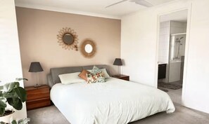 Ein Schlafzimmer mit einem Bett, Nachttischen, Lampen und einer Zimmerpflanze.