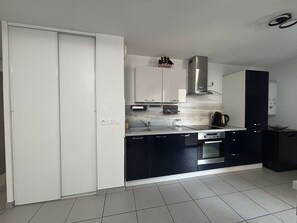 A modern kitchen with white and black cabinetry, stainless steel appliances, and a tiled floor. - Air-conditioned apartment - 4 guests (Argelès-sur-Mer)