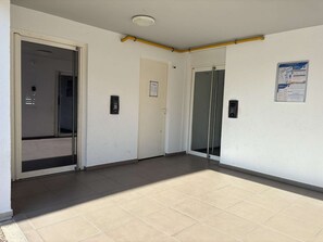 A hallway with a glass door, a door with a keypad, and a poster on the wall. - Air-conditioned apartment - 4 guests (Argelès-sur-Mer)