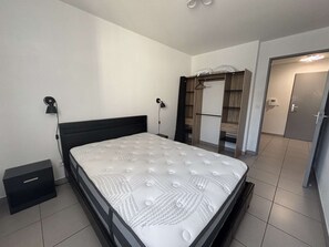Une chambre à coucher avec un lit, des lampes de chevet, une armoire et une porte donnant sur une autre pièce.