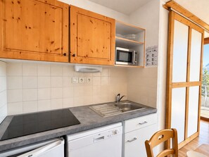 A kitchen with wooden cabinets, a microwave, a sink, and a dishwasher. - Apartment with south-facing terrace - 6 guests (Chamrousse)