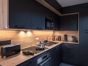 A modern kitchen with dark cabinetry, a wooden countertop, a built-in oven, and a microwave. - Apartment with village and mountain view - 6 guests (Notre-Dame-de-Bellecombe)