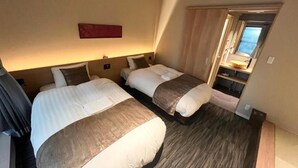 Une chambre d’hôtel avec deux lits, un plancher en bois, un mur d’accent rouge et une fenêtre donnant sur un paysage agréable.