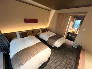 Hotellihuone, jossa on kaksi sänkyä, puulattia, punainen tehosteseinä ja ikkuna, josta on näkymä.