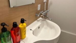 Un lavabo de salle de bain avec trois bouteilles de savon et un miroir au-dessus.