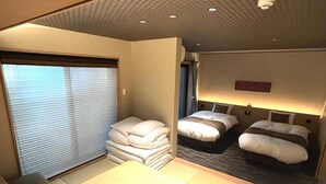 Une chambre d’hôtel équipée d’un lit, de tables de chevet, d’un bureau et d’une fenêtre avec des stores.