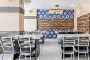 A dining area with multiple tables and chairs, a patterned wall, and a ceiling fan.