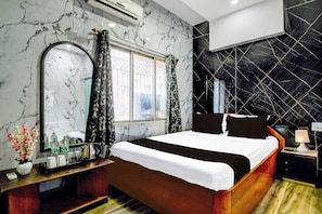 A hotel room with a bed, a nightstand, a mirror, a window with curtains, and a wall with a geometric pattern. - Hotel O Serampore Railway Station (Shrirampur)
