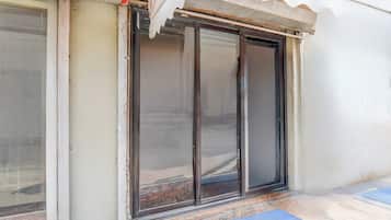 Una puerta corrediza de vidrio da a un espacio exterior cubierto con un tapete azul en el suelo.