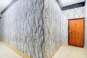 A hallway with marble walls, a wooden door, and a light-colored tiled floor.
