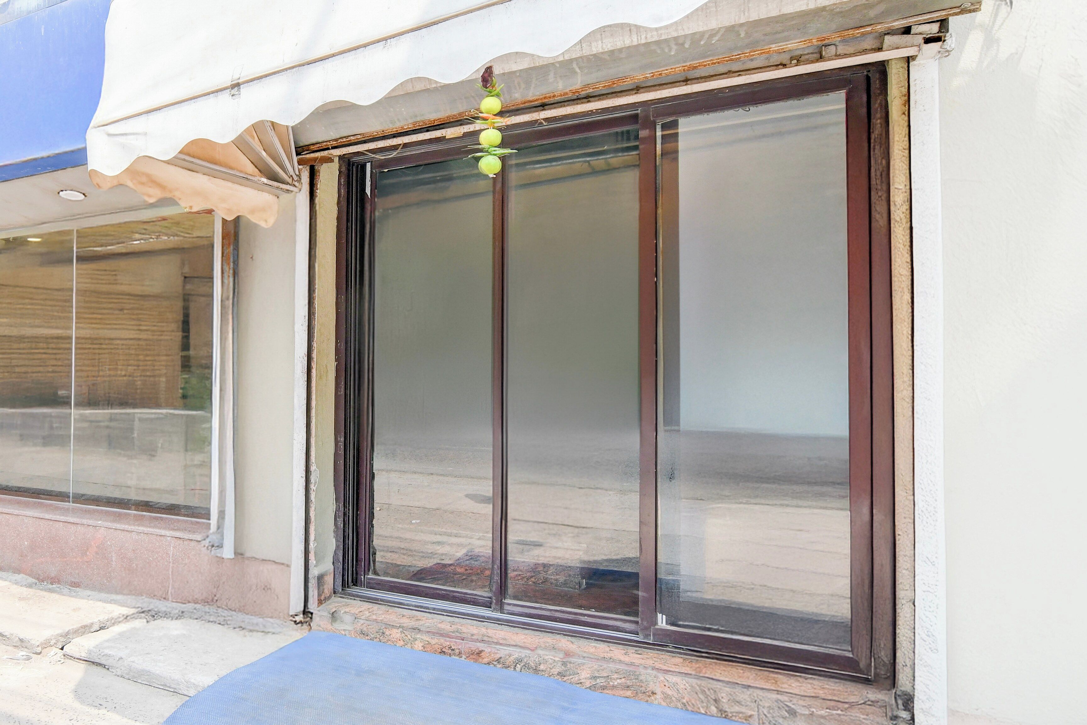 A building with a large sliding glass door, a small awning, and a stone wall.