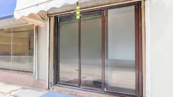 A building with a large sliding glass door, a small awning, and a stone wall.