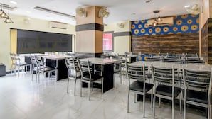Un comedor amplio con varias mesas y sillas, unidades de aire acondicionado y decoraciones murales con diseños.