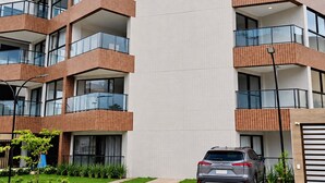 A multi-story building with a prominent 'SEASON SMART FLATS' sign, featuring balconies and a car parked in front. - Smart Flat Premium | Alexa | Porto City Center | 210 (Porto de Galinhas)