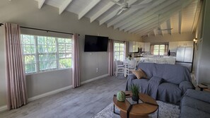 Ein geräumiges Wohnzimmer mit grauem Sofa, einem Couchtisch und einem an der Wand befestigten Flachbildfernseher.