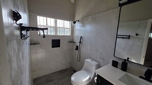 Ein Badezimmer mit Toilette, Dusche, Waschbecken und einem großen Spiegel.