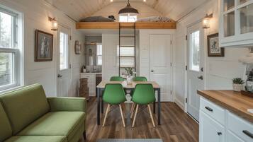 Une cuisine chaleureuse avec une table à manger, des chaises et une chambre à coucher située en mezzanine au-dessus.