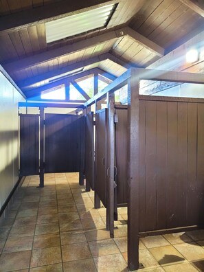 A row of wooden stalls with a tiled floor and a sloped ceiling with skylights.