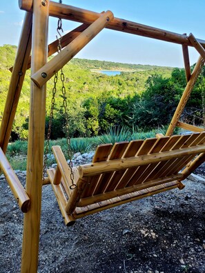 A wooden swing set with a view of a lake and greenery in the background.