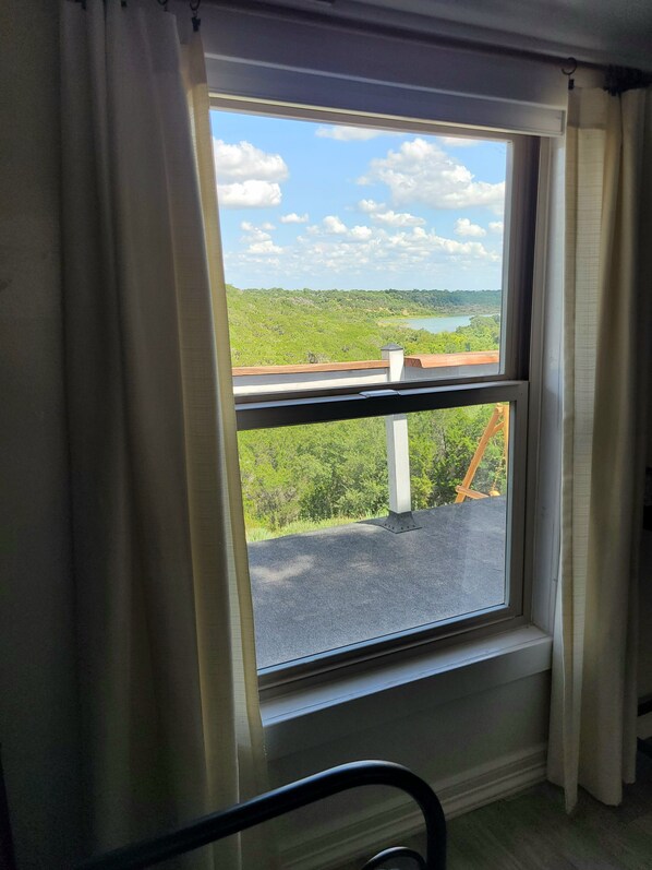 A window with a view of a green landscape and a body of water.