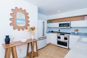Une cuisine moderne avec des meubles blancs, un four à micro-ondes, une cuisinière et un plan de travail en bois.