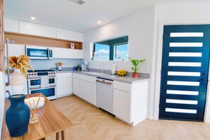 A modern kitchen with white cabinetry, a built-in oven, microwave, and a window above the sink.