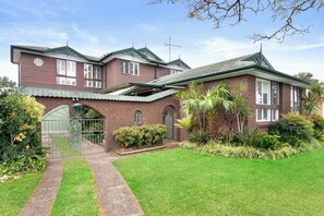 A two-story house with a brick facade, a green roof, and a gated entrance. - Spacious Family Home with Multiple Living Areas (Baulkham Hills)