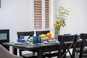 Una mesa de comedor preparada con platos, tazones y un florero con flores.