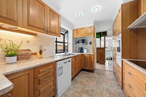 Una cocina moderna con armarios de madera, lavavajillas, microondas y fregadero.