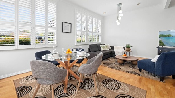 Ein modernes Wohnzimmer mit einem Glastisch, Sofas und einem Fernseher.