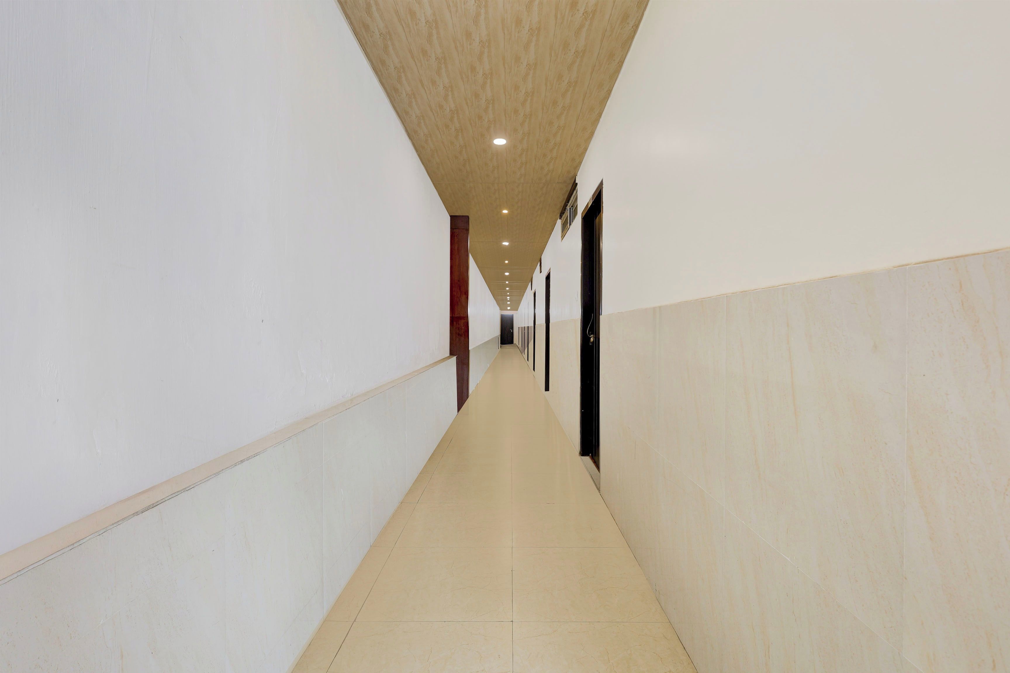 A long, narrow hallway with white walls and a wooden ceiling.