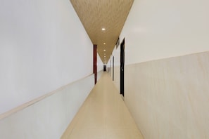 Un pasillo largo y estrecho con paredes blancas y techo de madera.