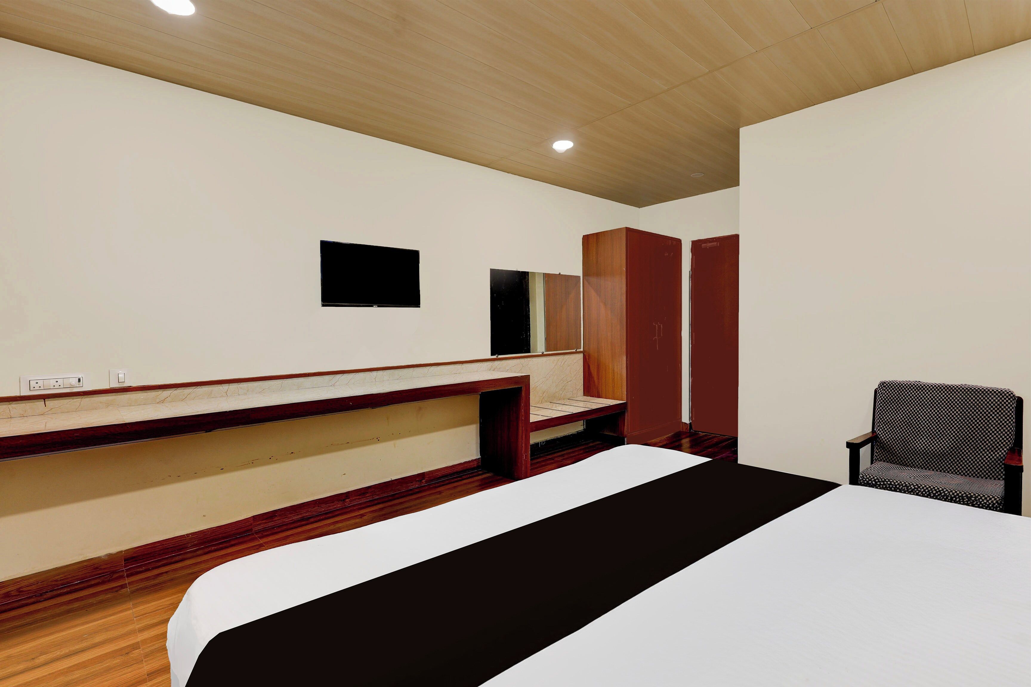 Una habitación de hotel con una cama, televisión, armario y una silla.