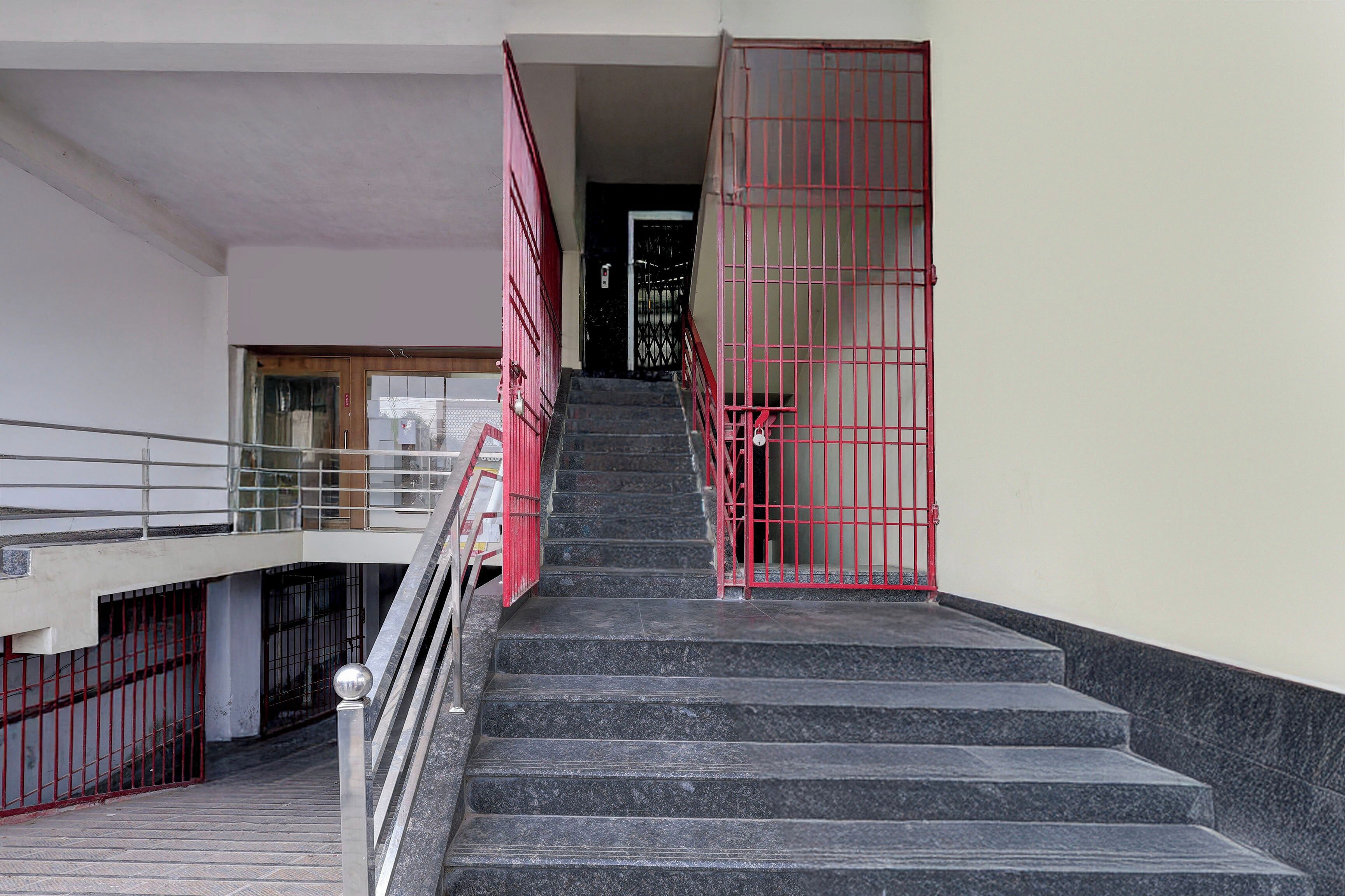 Un escalier avec des rampes en métal et une porte rouge en haut.