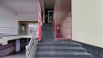 Un escalier avec des rampes en métal et une porte rouge en haut.