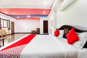 A hotel room with a bed, a red and white patterned runner, a wooden headboard, and a ceiling fan. - Townhouse CMR Complex Poddatur (Proddatur)