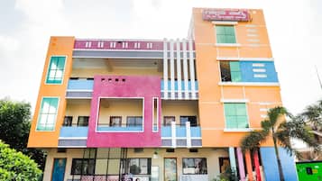 A multi-story building with a flat roof, multiple balconies, and a variety of window styles.