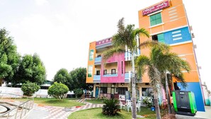 A multi-story building with a colorful facade, a visible signboard, and a paved entrance area with a small garden. - Townhouse CMR Complex Poddatur (Proddatur)
