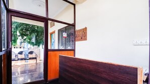 A room with a wooden bench, a glass door leading outside, and a wall-mounted electrical outlet. - Townhouse CMR Complex Poddatur (Proddatur)