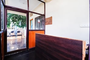 A room with a wooden bench, a glass door leading outside, and a wall-mounted electrical outlet. - Townhouse CMR Complex Poddatur (Proddatur)
