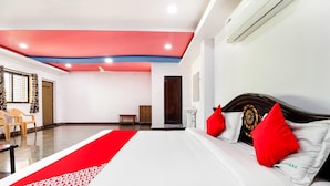 A hotel room with a bed, a red and white patterned runner, a wooden headboard, and a ceiling fan. - Townhouse CMR Complex Poddatur (Proddatur)