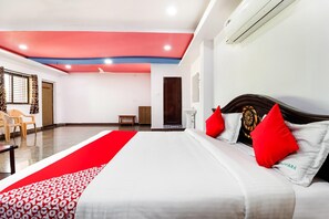 A hotel room with a bed, a red and white patterned runner, a wooden headboard, and a ceiling fan. - Townhouse CMR Complex Poddatur (Proddatur)