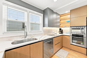 Een moderne keuken met een ingebouwde vaatwasser, roestvrijstalen apparatuur en houten kastjes.