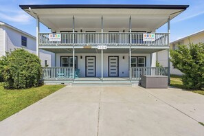 Een tweelaags gebouw met een overdekte veranda, huisnummer 1104, en een bordje dat aangeeft dat het een vakantiewoning is.