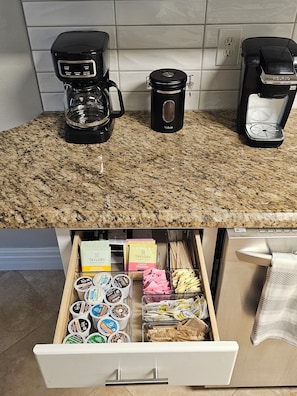 Eine Küche mit Kaffeemaschine, Wasserkocher und einer Schublade voller Lebensmittel.