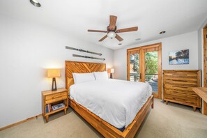A bedroom with a wooden headboard, a bed with white bedding, a nightstand with a lamp, a wooden dresser, and a ceiling fan. - New! Ski Days + Sunset Après | 3BR Mountain Retreat | Walk to Ski + Garage (Telluride)