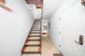 A staircase with wooden steps and beige mats, leading to a room with a bed and a door. - New! Ski Days + Sunset Après | 3BR Mountain Retreat | Walk to Ski + Garage (Telluride)