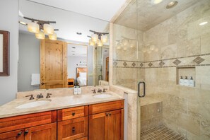 Un baño moderno con tocador doble, un espejo grande y zona de ducha con puerta de cristal.